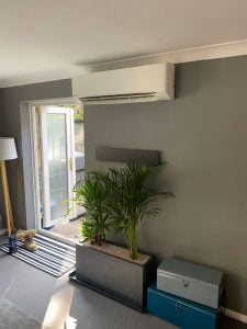 Wall-mounted Panasonic split air conditioning unit installed above a garden door in a residential room
